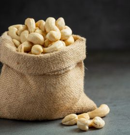 Raw cashews nuts in bag on dark background